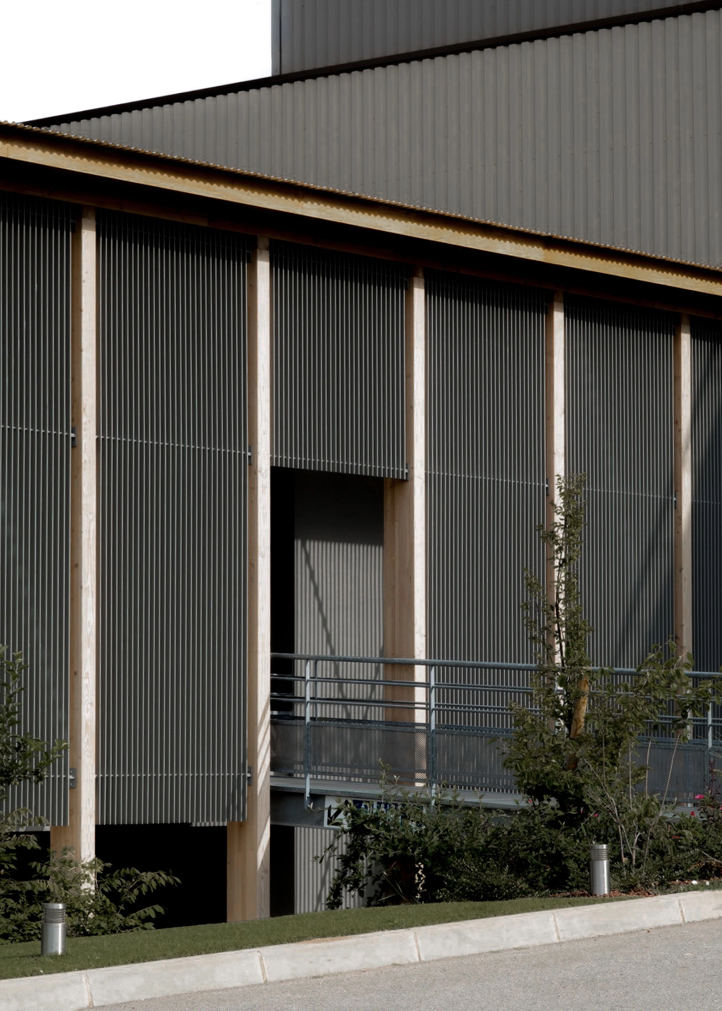 Façade de l'extension du siège des Transports Galtier avec structure en bois, brise-soleil métalliques et coursive extérieure