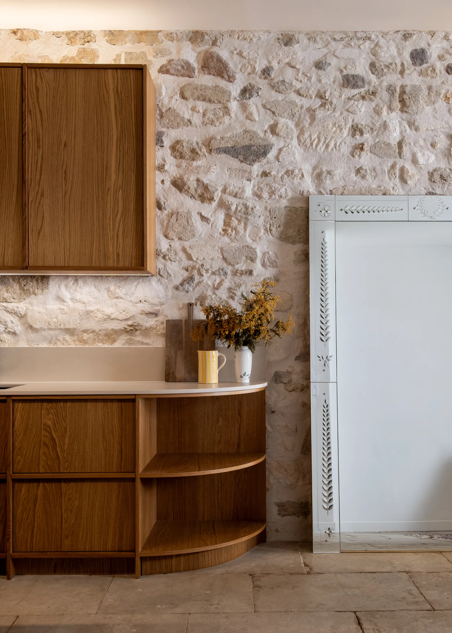 Cuisine rénovée de lappartement Maréchal à Montpellier, avec mobilier bois, mur en pierre apparente et miroir ancien.