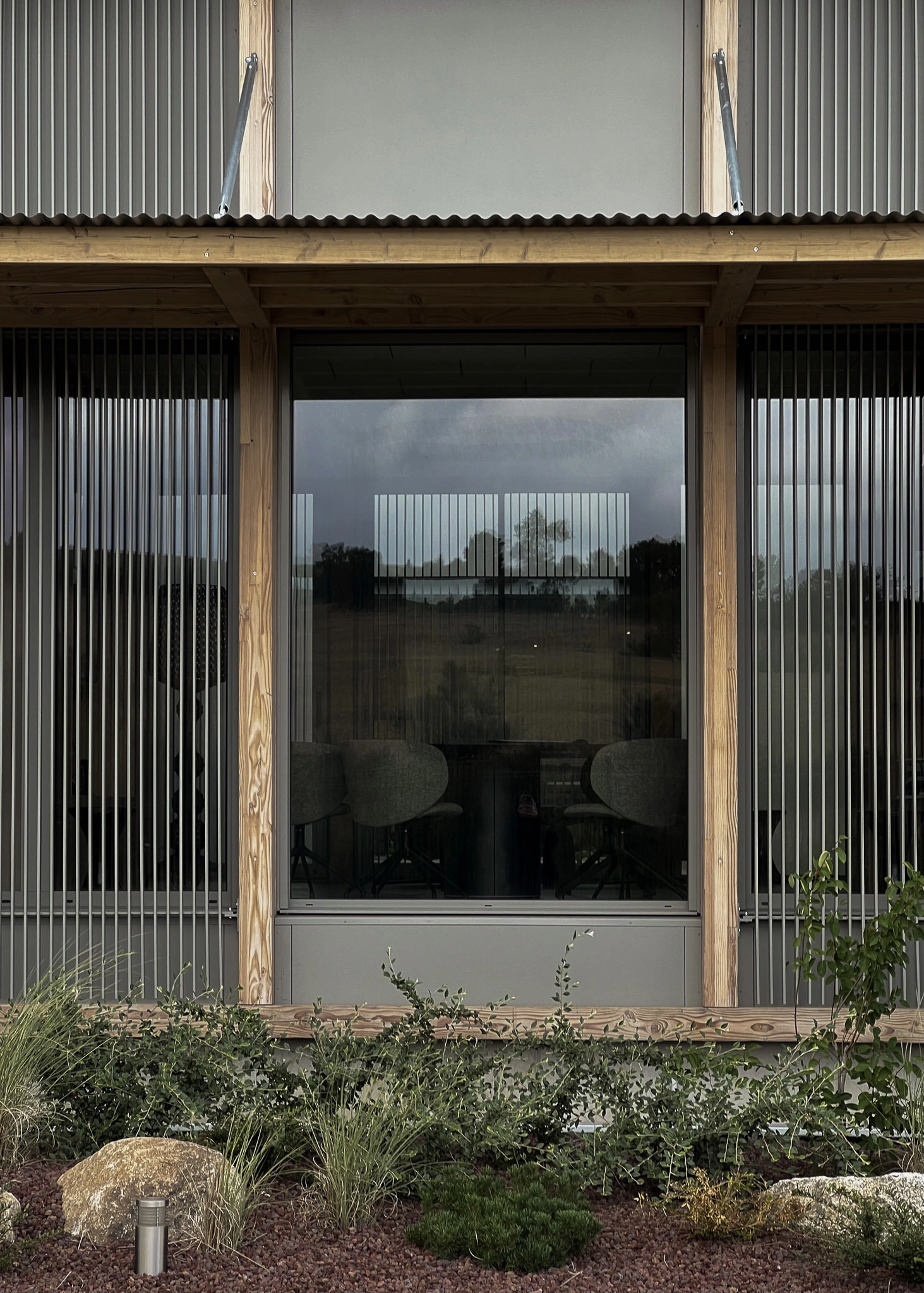 Baie vitrée encadrée de bois et de brise-soleil métalliques sur la façade des Transports Galtier