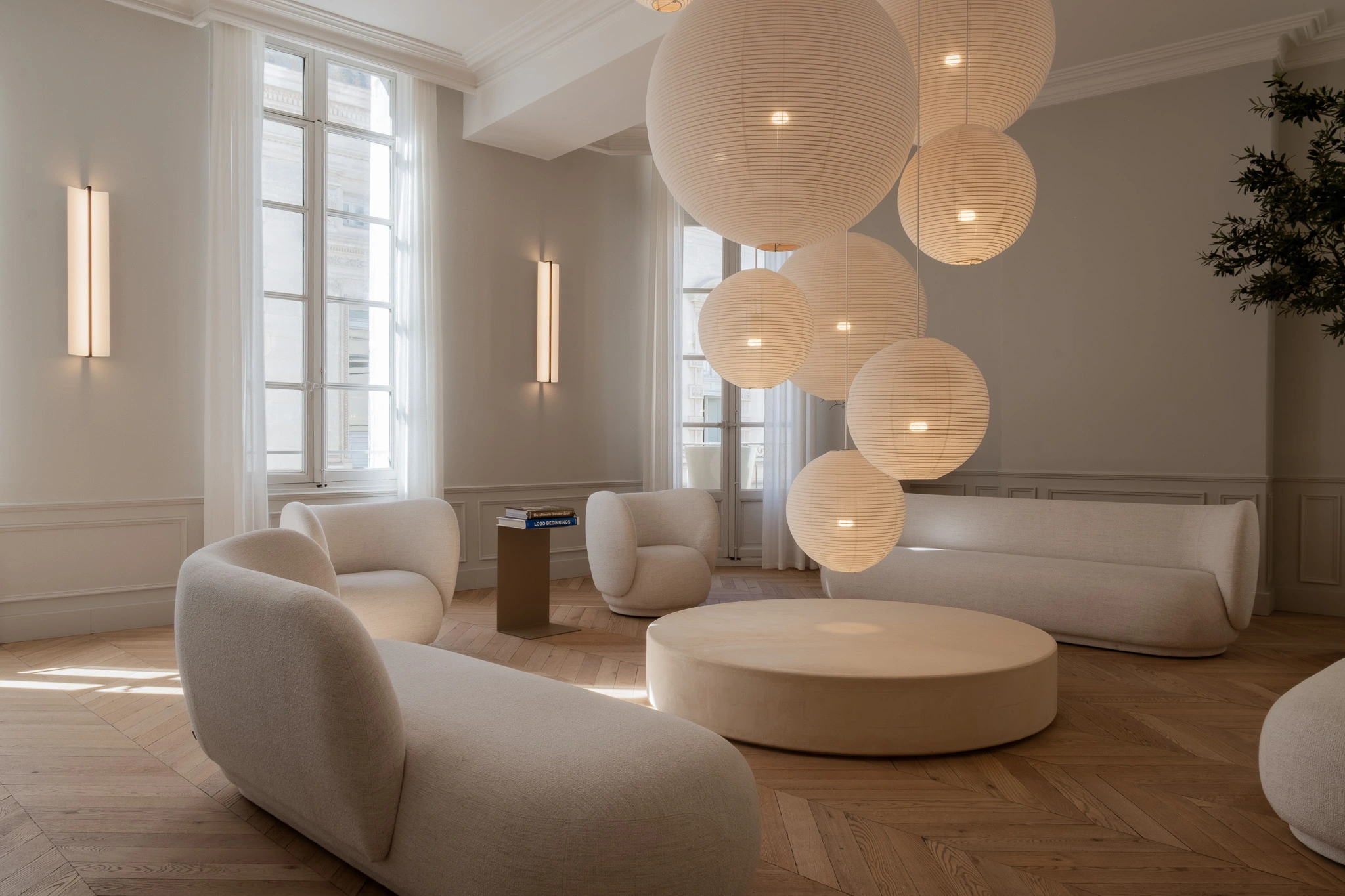 Salle d'attente du cabinet de chirurgie esthétique du Dr. Lange à Montpellier avec mobilier aux formes courbes et suspensions sphériques.