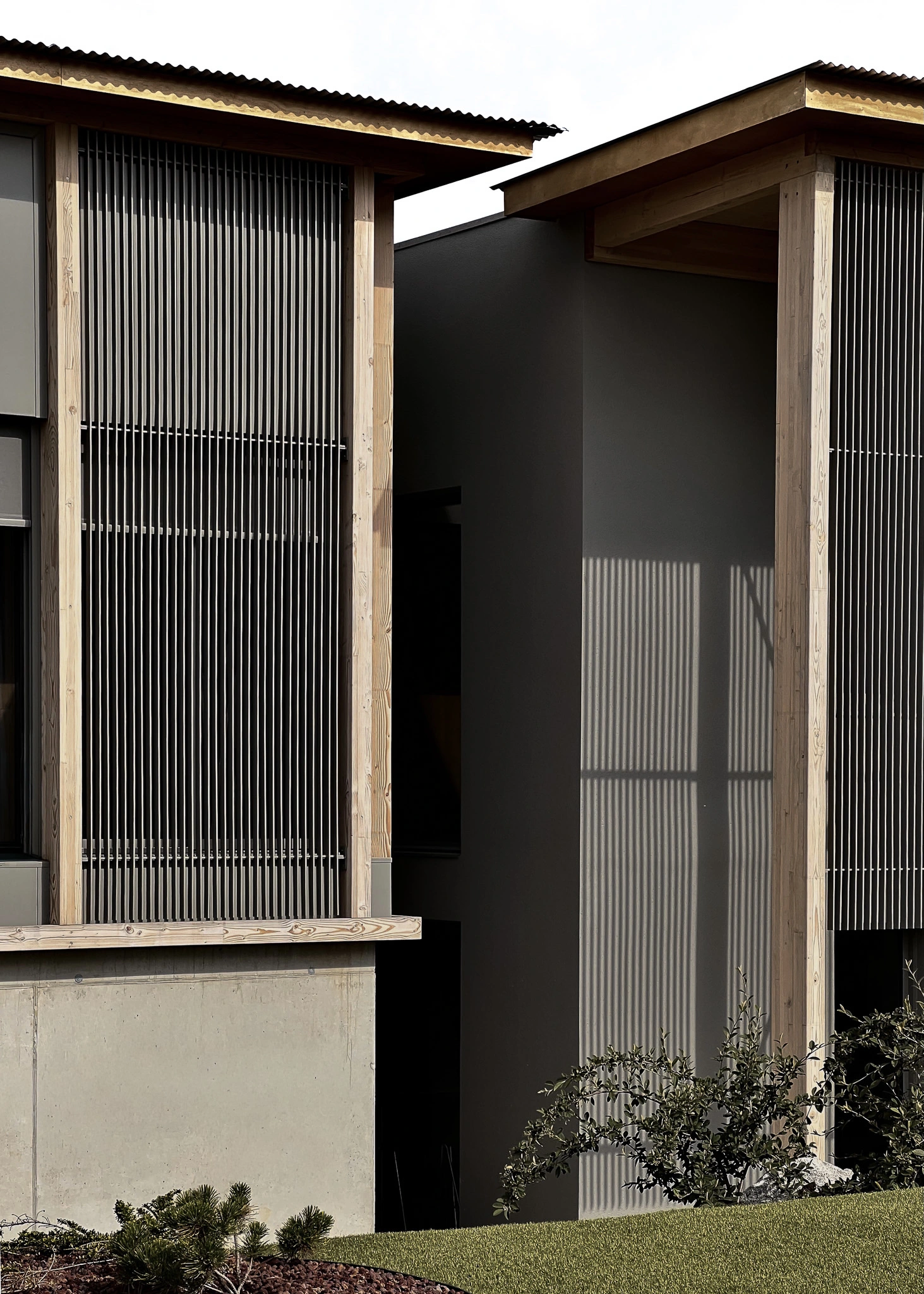 Jonction des volumes entre l'extension et l'existant du siège des Transports Galtier, avec structure en bois et brise-soleil métalliques.