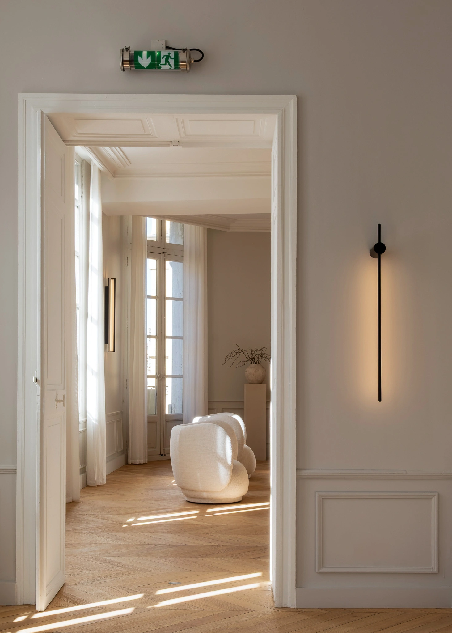 Passage vers la salle d'attente du cabinet du Dr. Lange à Montpellier, dans un appartement haussmannien avec parquet et moulures.