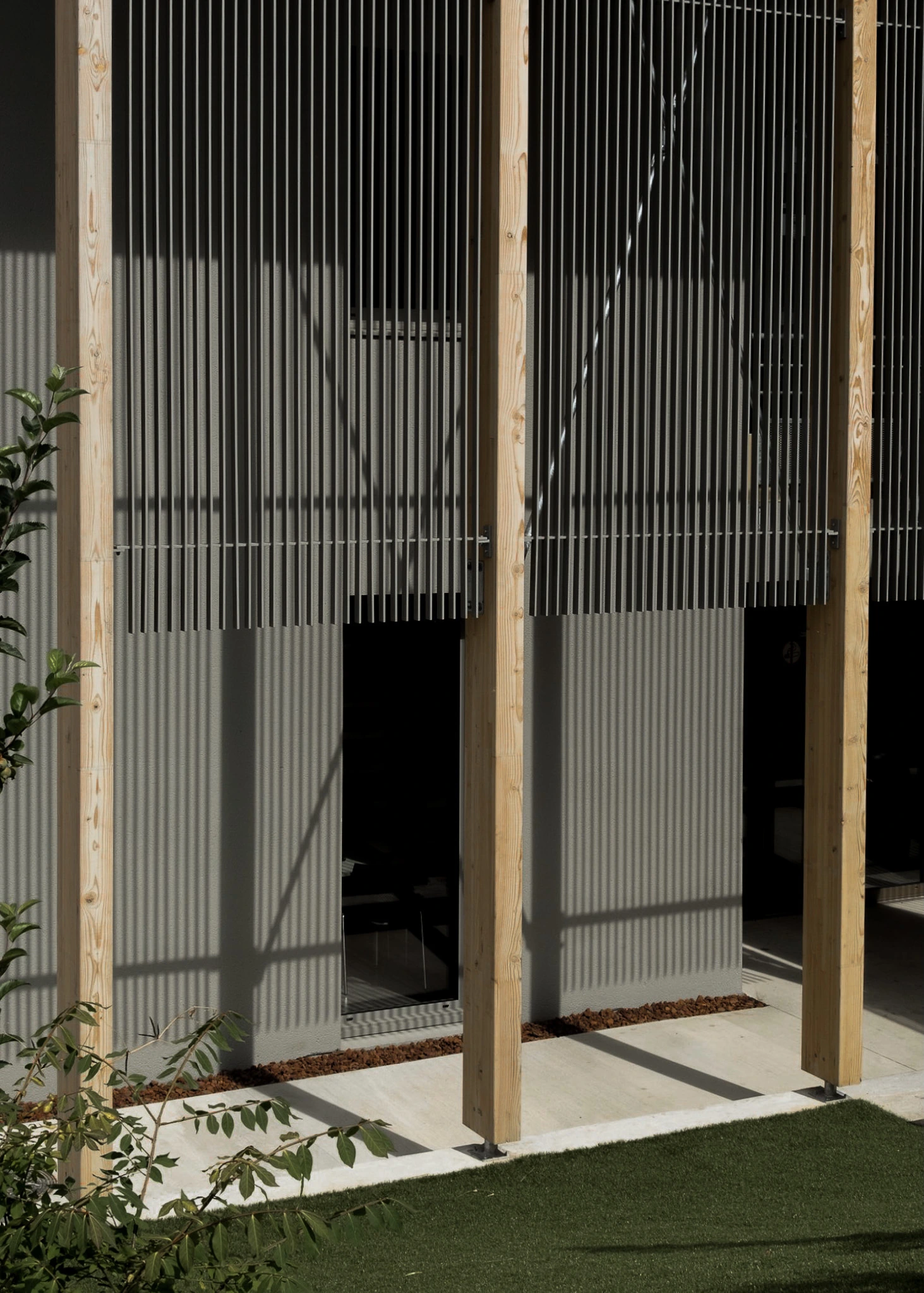 Brise-soleil métalliques devant la façade du siège des Transports Galtier, entre poteaux bois et jeux d'ombres